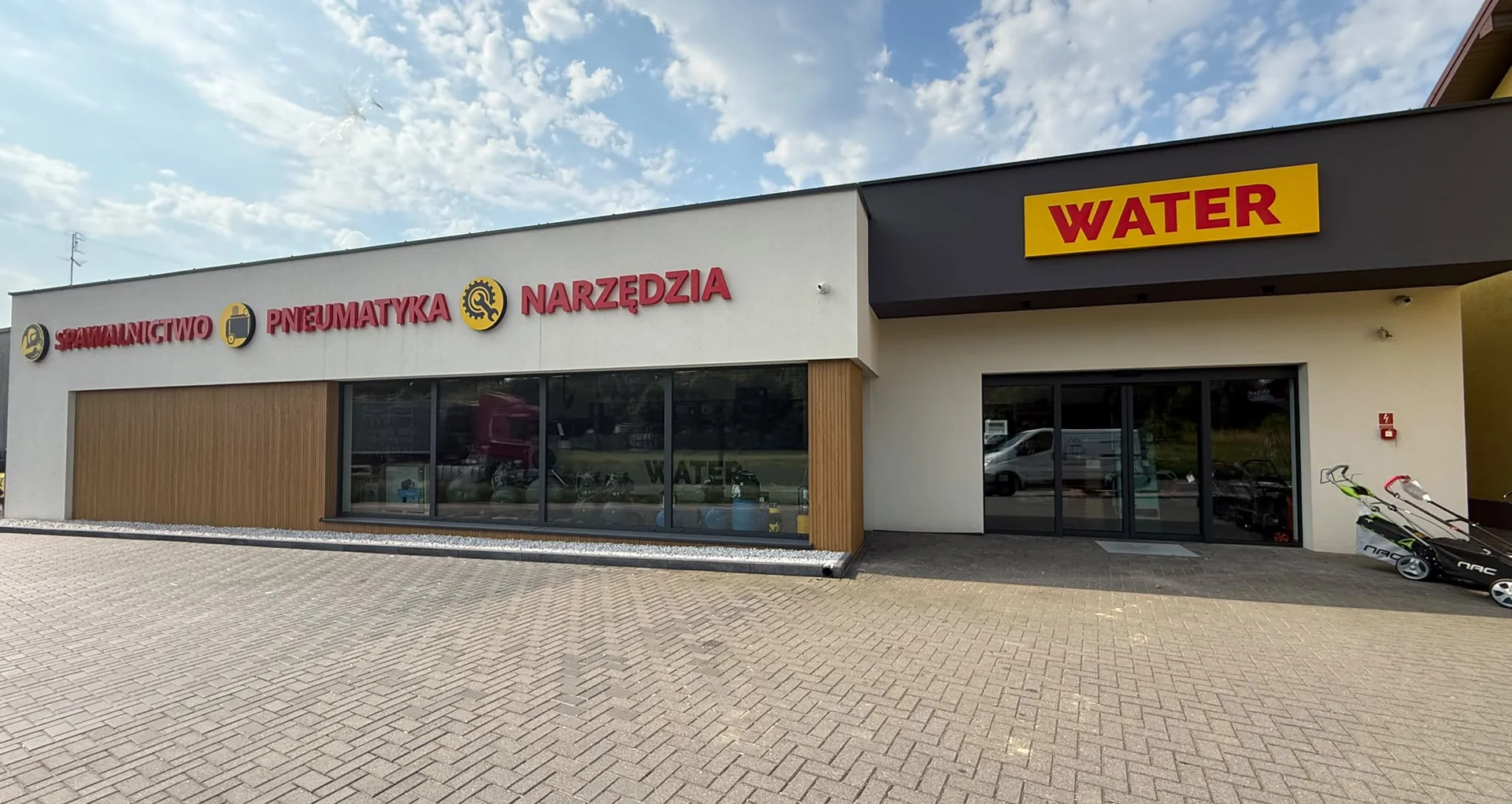 Budynek sklepu WATER przy ulicy Wieluńskiej 46A w Kłobucku: szara elewacja z żółtym szyldem